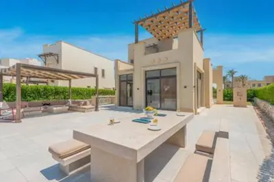 a patio with a table and benches in front of a building at The Lakefront Villa 4BR at Cyan ElGouna in Hurghada