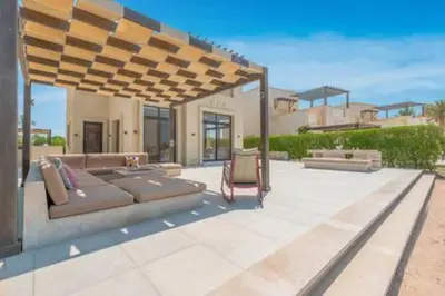 a patio with a couch under a wooden pergola at The Lakefront Villa 4BR at Cyan ElGouna in Hurghada