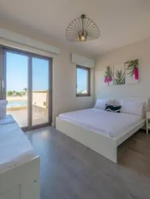 a white bedroom with a large bed and a large window at The Lakefront Villa 4BR at Cyan ElGouna in Hurghada