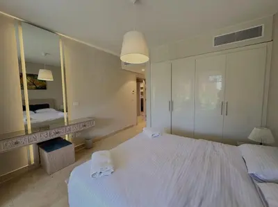 a bedroom with a large white bed and a mirror at Marvelous 2BR - Free Beach Access and Pool Access In Mangroovy in Hurghada