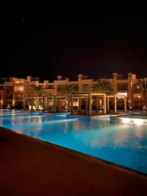 a large swimming pool in front of a building at night at Marvelous 2BR - Free Beach Access and Pool Access In Mangroovy in Hurghada