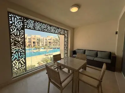a living room with a table and a large window at Marvelous 2BR - Free Beach Access and Pool Access In Mangroovy in Hurghada
