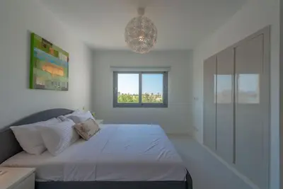 a white bedroom with a bed and a window at Elegant 3BR on Swan Lake Crystal Lagoon at Elgouna Families Only in Hurghada