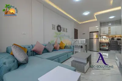 a living room with a blue couch and a kitchen at The Awesome 3-Bedroom Apartment & 2 bathroom in Al-Ahyaa Hurghada in Hurghada