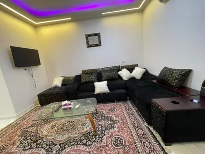 a living room with a black couch and a tv at استديو فندقى على البحر كمبوند بريستيجا اول طلعة فلفله الشيراتون in Hurghada
