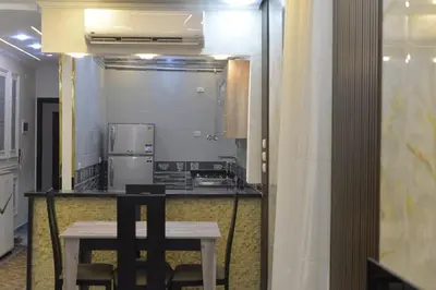 a kitchen with a table and a stove and a refrigerator at برج النيل بزنس in Jazīrat al ‘Awwāmīyah