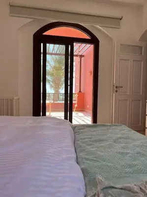 a bedroom with a bed and an open door at Cozy Townhouse in West Golf - El Gouna in Hurghada