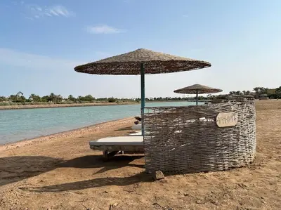 a group of chairs and umbrellas on a beach at Cozy Townhouse in West Golf - El Gouna in Hurghada