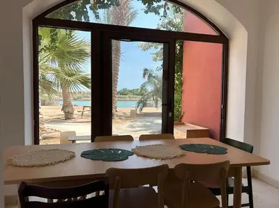 a dining room with a table and a large window at Cozy Townhouse in West Golf - El Gouna in Hurghada