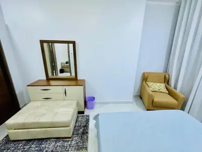 a bedroom with a bed and a mirror and a chair at Abbady tower in Jazīrat al ‘Awwāmīyah