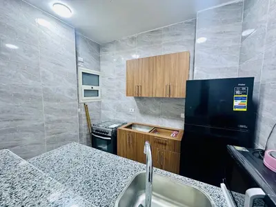 a small kitchen with a sink and a black refrigerator at Abbady tower in Jazīrat al ‘Awwāmīyah