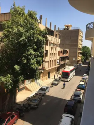 a city street with parked cars and a bus at Abbady tower in Jazīrat al ‘Awwāmīyah