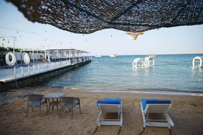 a beach with chairs and a table and a dock at CC Luxurious Apartment in Hurghada