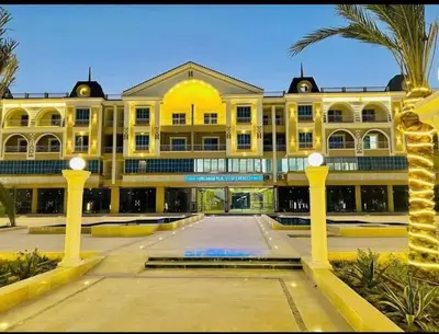 a large yellow building with a palm tree in front of it at Hurghada Hub in Hurghada