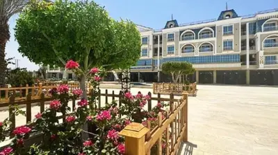 a building with pink flowers in front of a fence at Hurghada Hub in Hurghada