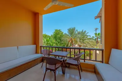 a balcony with a table and chairs and a large window at Cozy apartment with a pool in South Marina-Elgouna in Hurghada
