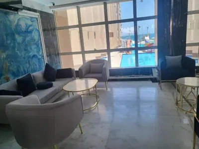 a living room with a couch and tables and a pool at Juliana Beach Aqua park in Hurghada