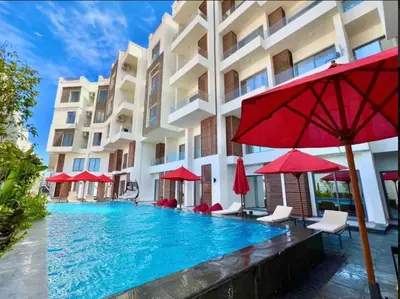 a swimming pool in front of a building with red umbrellas at Lavish suite 97m wifi sea view apt boutique resort in Hurghada