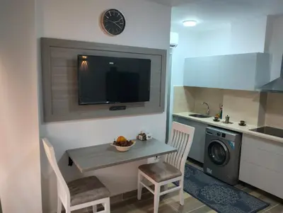 a small kitchen with a table and chairs and a clock at Petite Perle in Port Ghalib