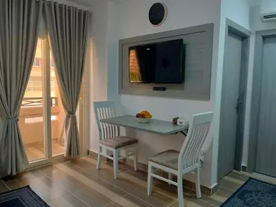 a dining room with a table and chairs and a television at Petite Perle in Port Ghalib