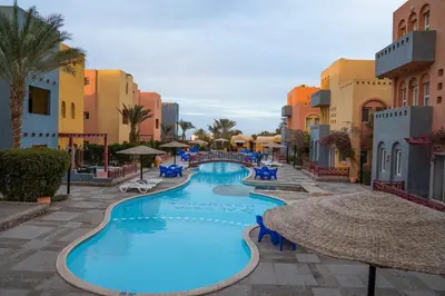 a resort swimming pool with chairs and umbrellas at Al Dora Resort All Inclusive Hotel in Hurghada