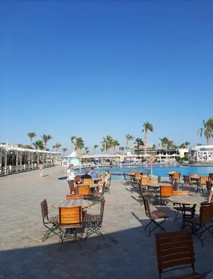a group of tables and chairs next to a swimming pool at قرية ميراج باي in Hurghada