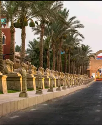 a row of statues next to a street with palm trees at قرية ميراج باي in Hurghada