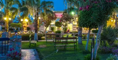 a park with benches and palm trees at night at قرية ميراج باي in Hurghada