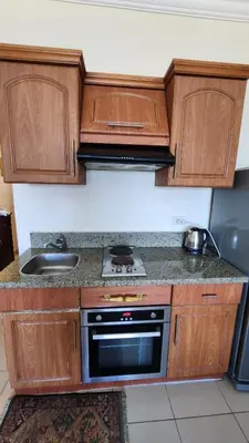 a kitchen with wooden cabinets and a stove top oven at Studil for rent old Sheraton 205 in Hurghada