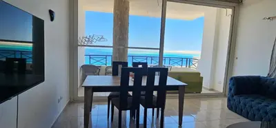 a dining room with a table and chairs and a view of the ocean at Sea view apartment 10 , in city center front of the sea F 10 in Hurghada