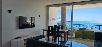 a living room with a dining table and a view of the ocean at Sea view apartment 10 , in city center front of the sea F 10 in Hurghada