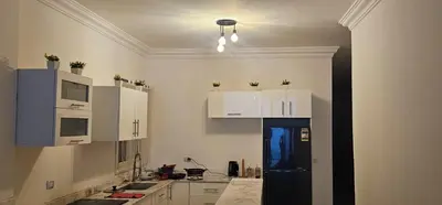 a kitchen with white cabinets and a black refrigerator at Sea view apartment 10 , in city center front of the sea F 10 in Hurghada