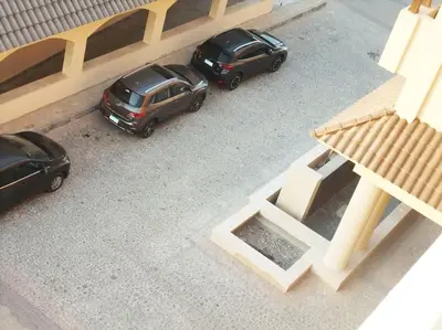 two cars parked in a parking lot next to a building at Jomana Aldau Heights Hurghada rent one bedroom apartment in Hurghada