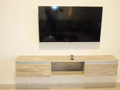 a large television on a wall with a wooden bench at Jomana Aldau Heights Hurghada rent one bedroom apartment in Hurghada