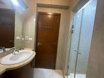 a bathroom with a sink and a shower and a wooden door at El gouna , Red sea in Hurghada