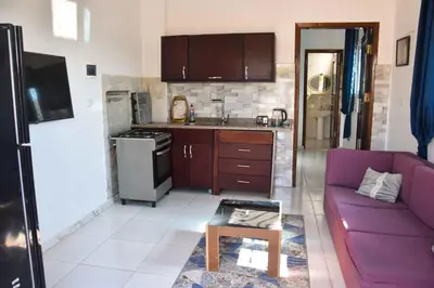 a living room with a purple couch and a kitchen at Amenirdis Villa in Al Qurnah