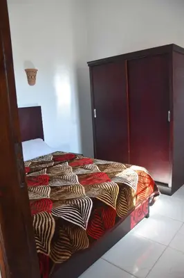 a bedroom with a bed and a wooden cabinet at Amenirdis Villa in Al Qurnah