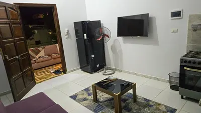 a living room with a tv and a table in a room at Amenirdis Villa in Al Qurnah