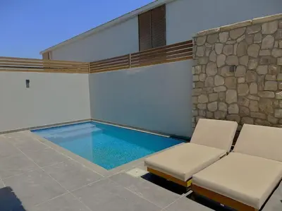 a swimming pool with two chairs and a stone wall at Unique 2BR Villa - Private Pool In Bali-ElGouna in El Gouna