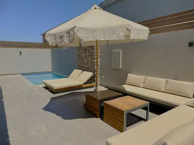 a patio with a couch and an umbrella at Unique 2BR Villa - Private Pool In Bali-ElGouna in El Gouna