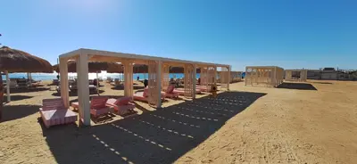 a group of chairs and umbrellas on a beach at Cozy 1BR in Princess Resort with Pools & Private Beach in Hurghada
