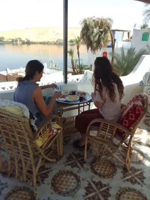 two women sitting at a table on a balcony at Nubian Life Nile View in Aswan