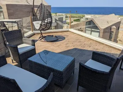 a patio with tables and chairs and the ocean at Elevated Sea View 2BR Standalone Free Beach & Pool in Somabay in Hurghada