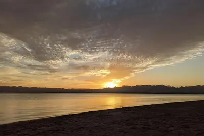 a sunset on a beach with the sun setting at Elevated Sea View 2BR Standalone Free Beach & Pool in Somabay in Hurghada
