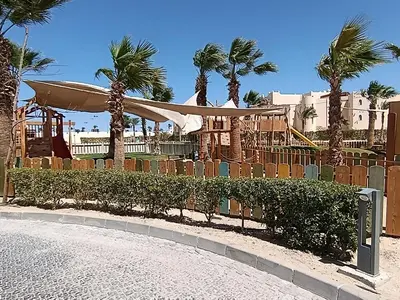 a park with a fence and palm trees and a playground at Mesca Chalet Soma Bay in Hurghada