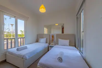 two beds in a room with a large window at Gouna Retreat 2BR Apt Waterside Hot Tub & Pool in Hurghada