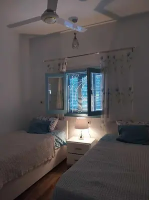 a bedroom with two beds and a ceiling fan at Ahsaya-house beautiful new home in ‘Ezbet Abu Ḥabashi