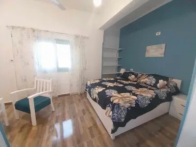 a bedroom with a bed and a chair and a window at Ahsaya-house beautiful new home in ‘Ezbet Abu Ḥabashi