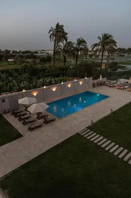 a swimming pool with chairs and umbrellas in a backyard at Royal Nile Suites - Nile View 1 in Luxor