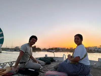 a man and a woman sitting next to the water at Royal Nile Suites - Nile View 1 in Luxor